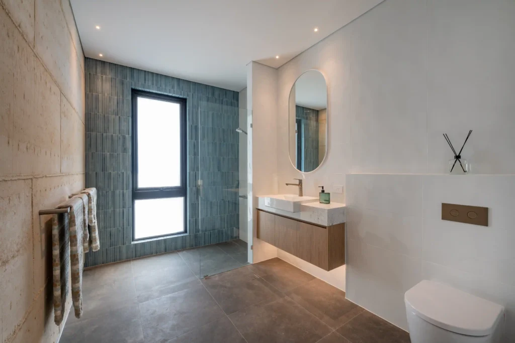 Modern living room with wooden flooring, gray walls, and a cozy seating area with natural lighting.