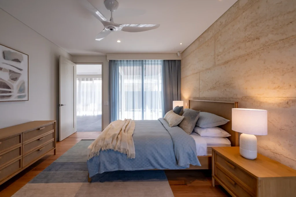 Bright bedroom with a double bed, wooden floors, bedside lamps, and a large window.