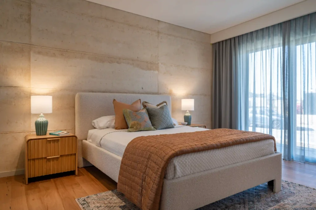 Cozy bedroom interior with wooden ceiling, bed with white bedding, and warm lighting.