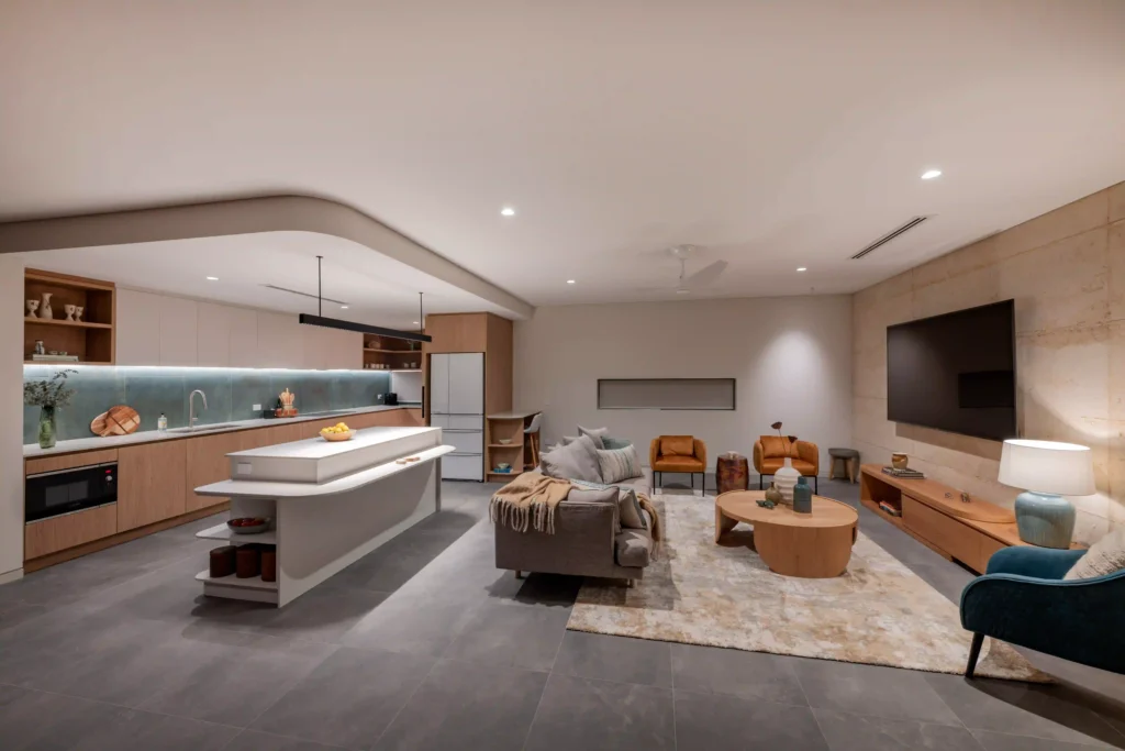 Open-concept kitchen and living area with neutral tones and wood cabinetry.