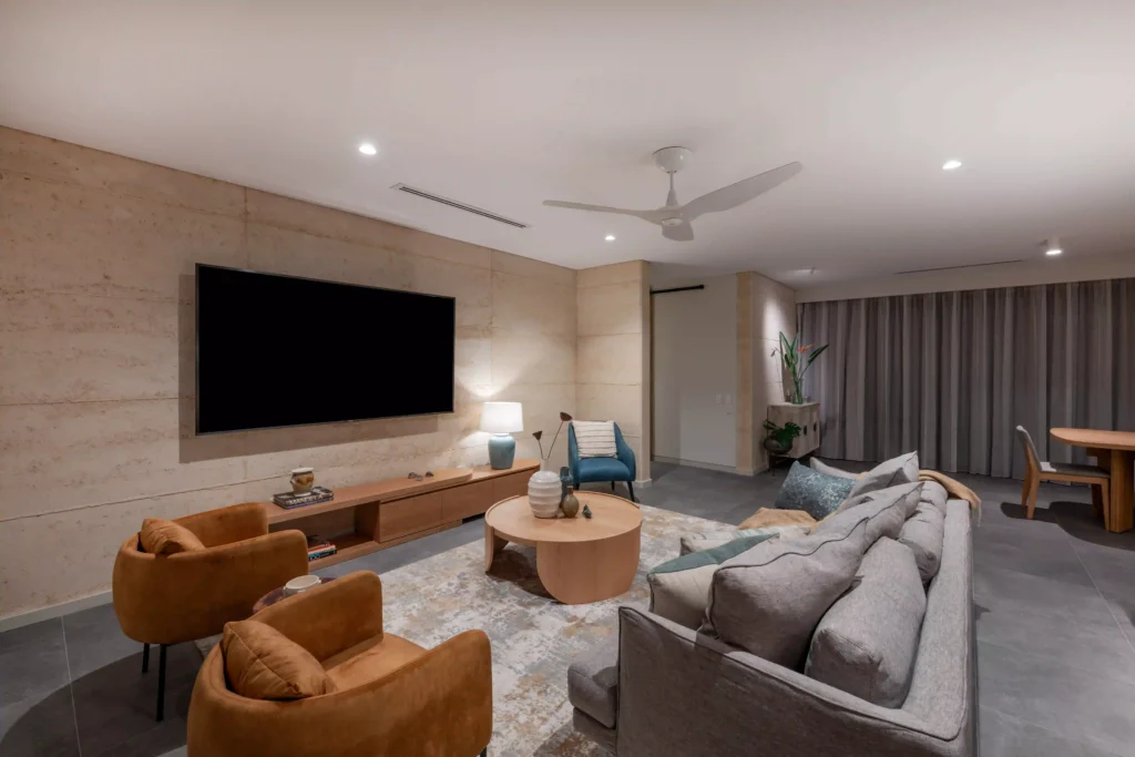 Open living room with modern furniture, large TV, and warm lighting.