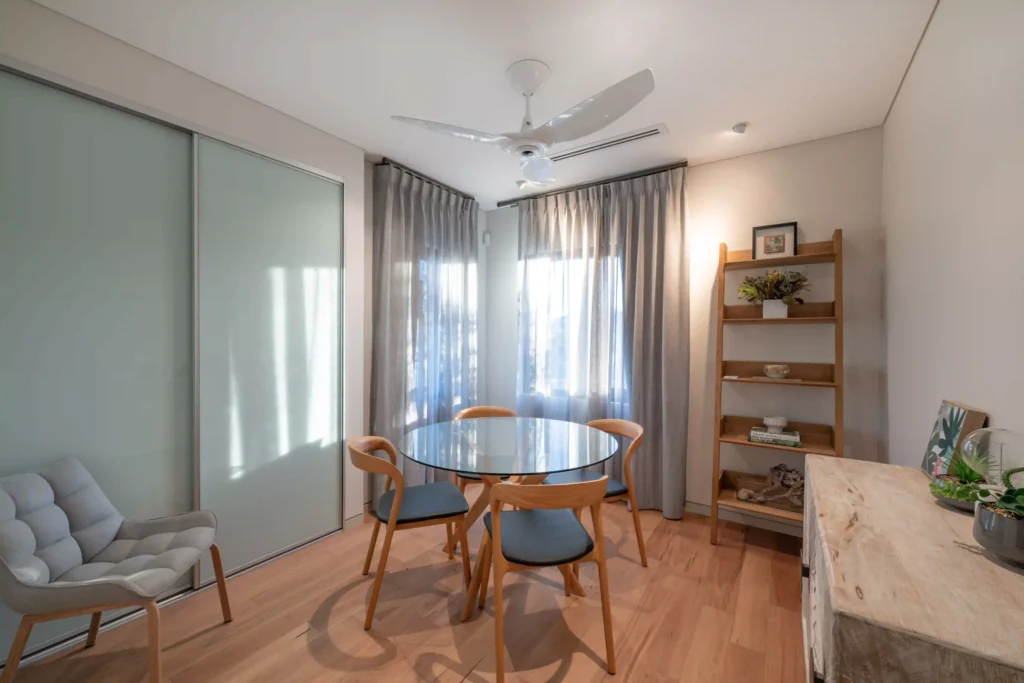 Spacious bedroom with wood accents, large windows, and a cozy bed with neutral tones.