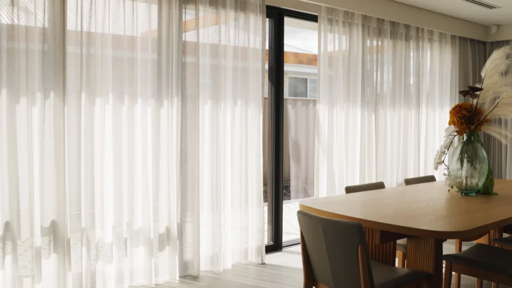 Interior space with floor-to-ceiling curtains, a lounge chair, and soft natural light.